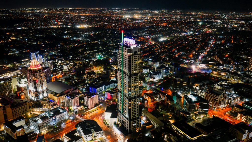A stunning aerial photograph of Sandton's illuminated skyline at night, showcasing vibrant city lights and skyscrapers.